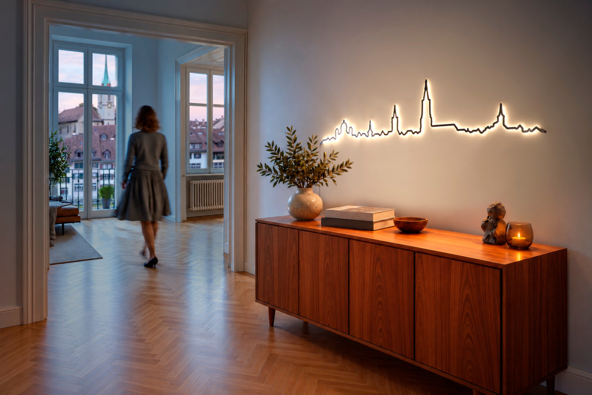 Beleuchtete Kontura Skyline über einem Nussbaum-Sideboard im Flur einer Altbauwohnung, im Hintergrund eine Frau und der Blick über die Dächer der Stadt.