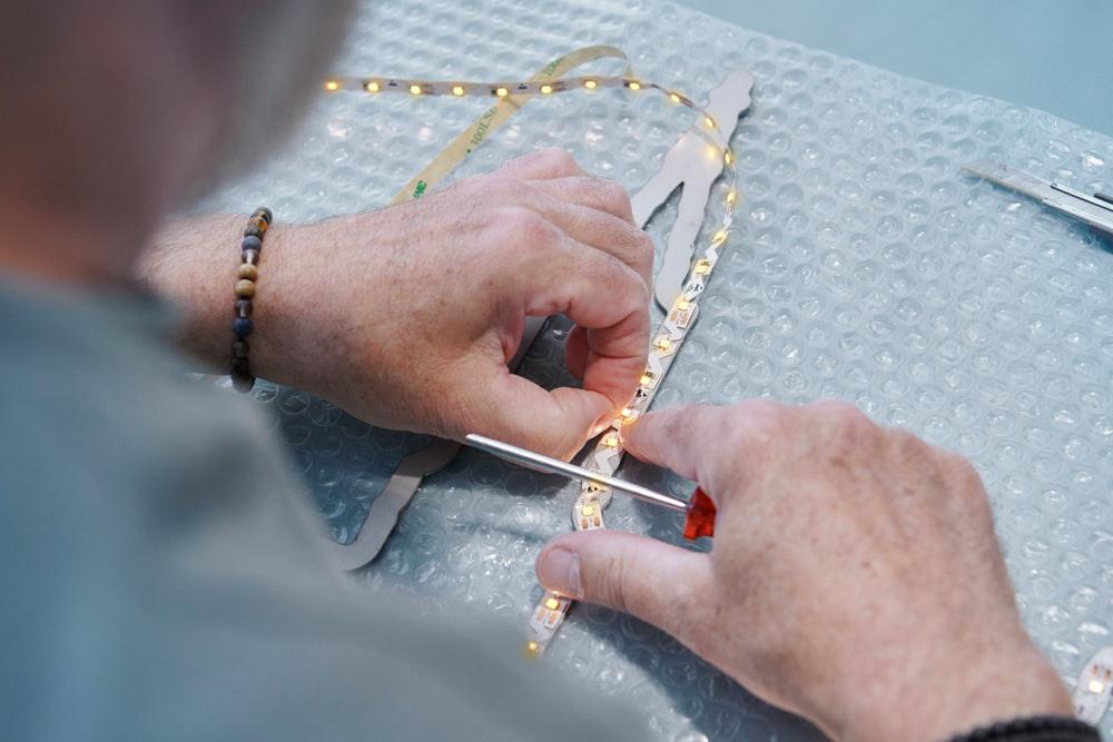 Arbeitsschritt 1: LED-Band wird von Hand in das Chromstahl-Profil eingesetzt